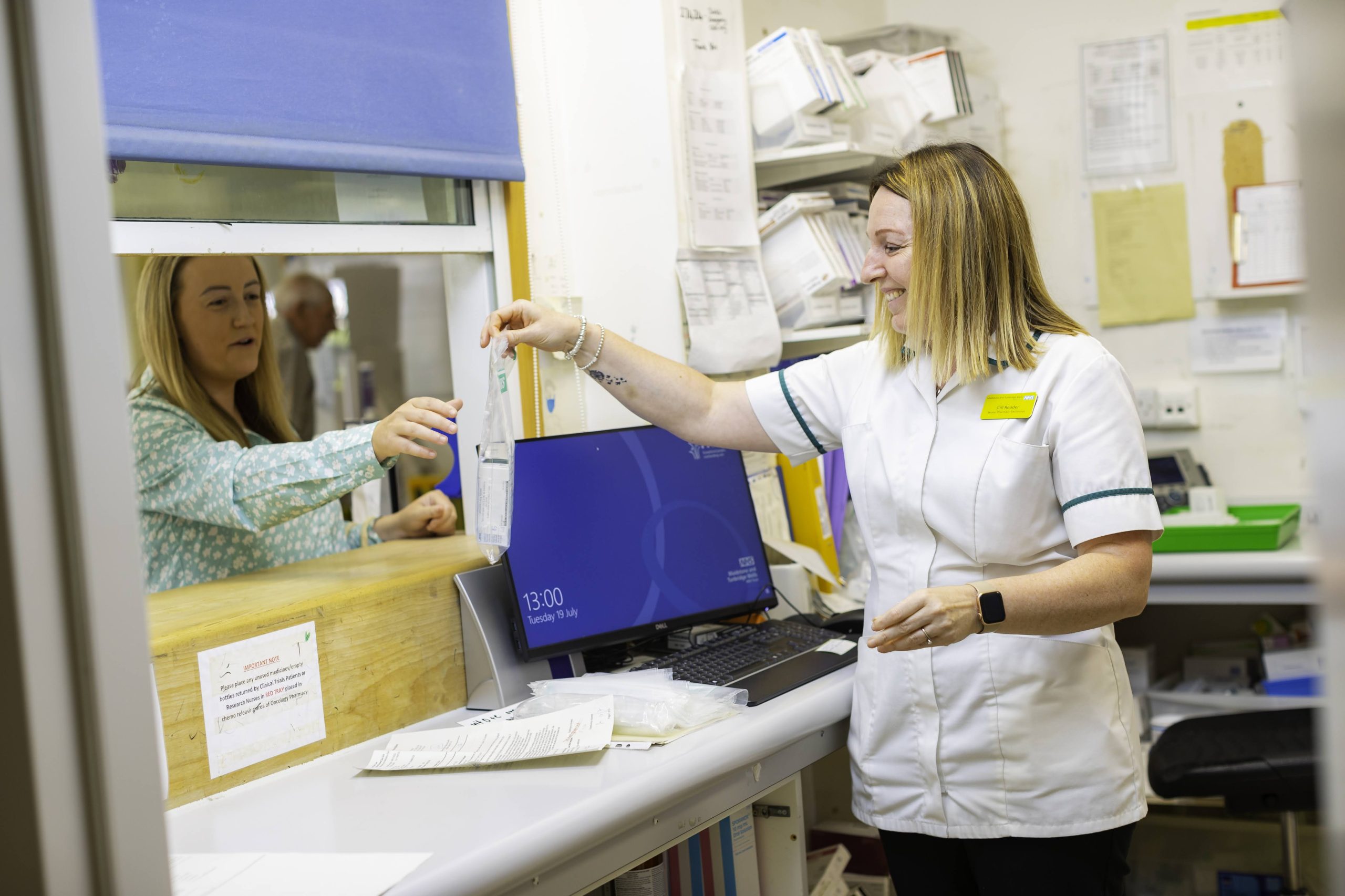 A pharmacist handing a patient their prescription at a pharmacy